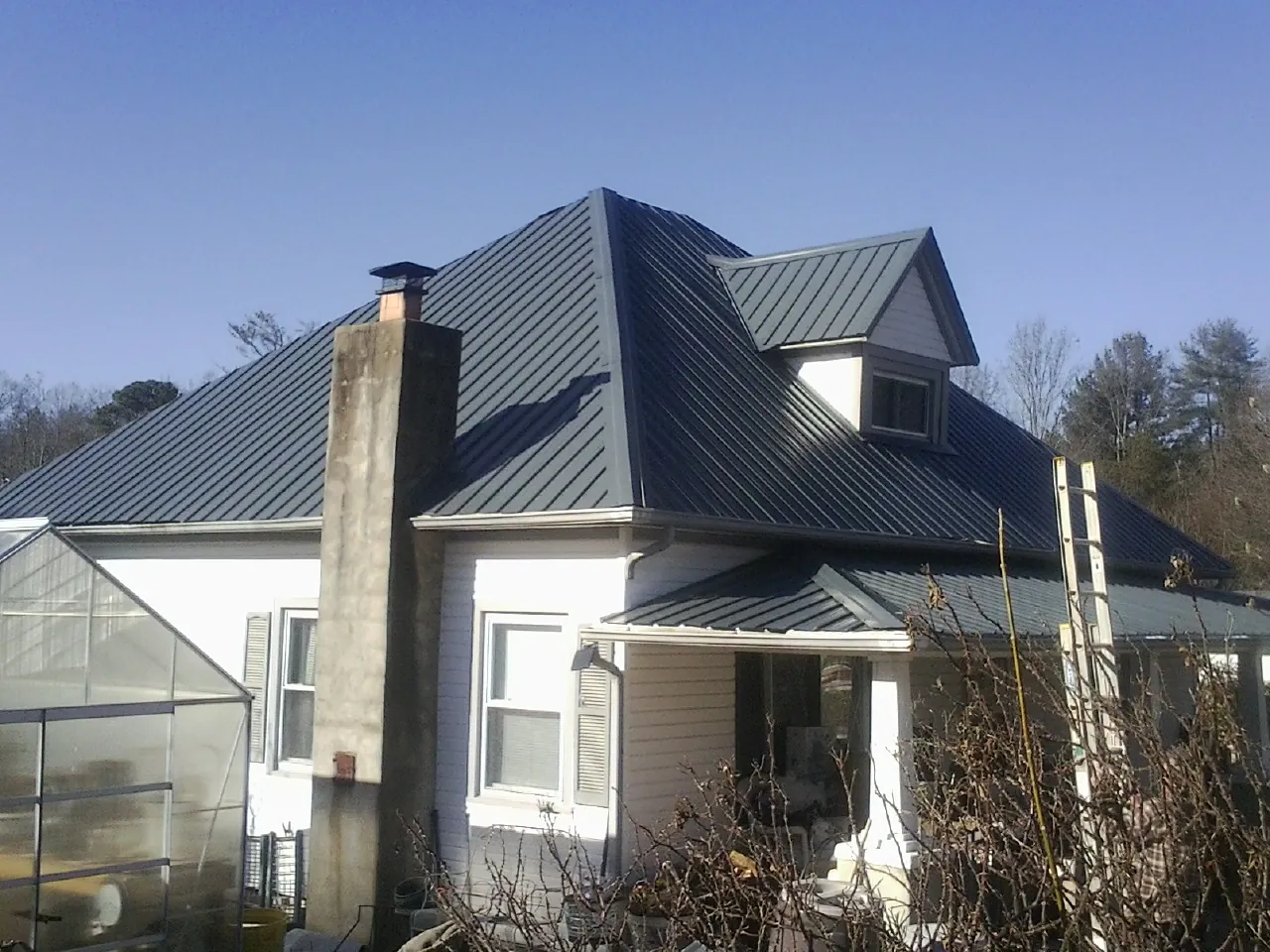 Dark blue standing seam metal roof on a white farmhouse with dormer — Slate & Tile Roof Repair by Roofing Brothers in Register