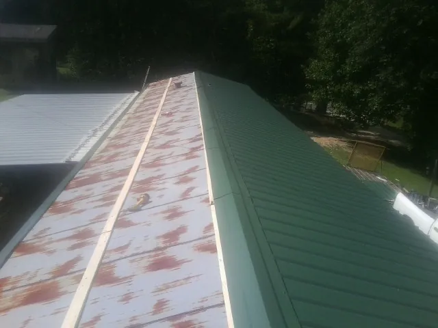 Old rusted panels beside newly installed green metal roofing — Wind Damage Roof Repair by Roofing Brothers in Register