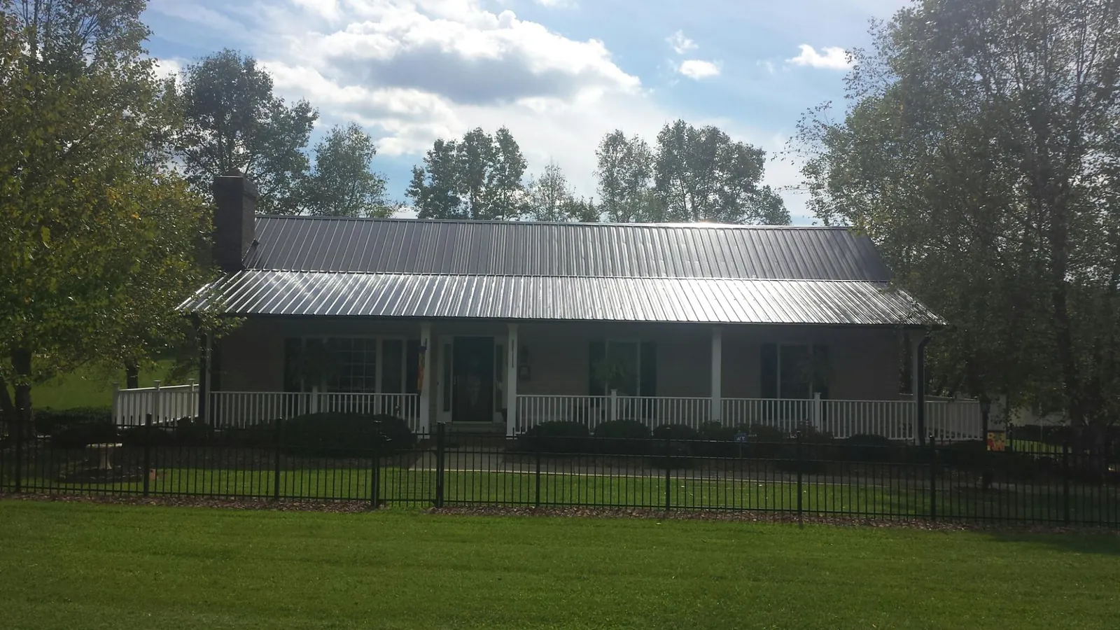 Gray metal roof on a brick ranch with a full width front porch — Gutter Guard Installation work by our crew in Register