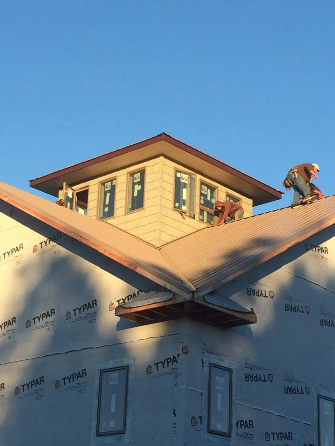 Roofers working around a rooftop cupola on a new metal roof at sunset — Roof Waterproofing in Register by Roofing Brothers